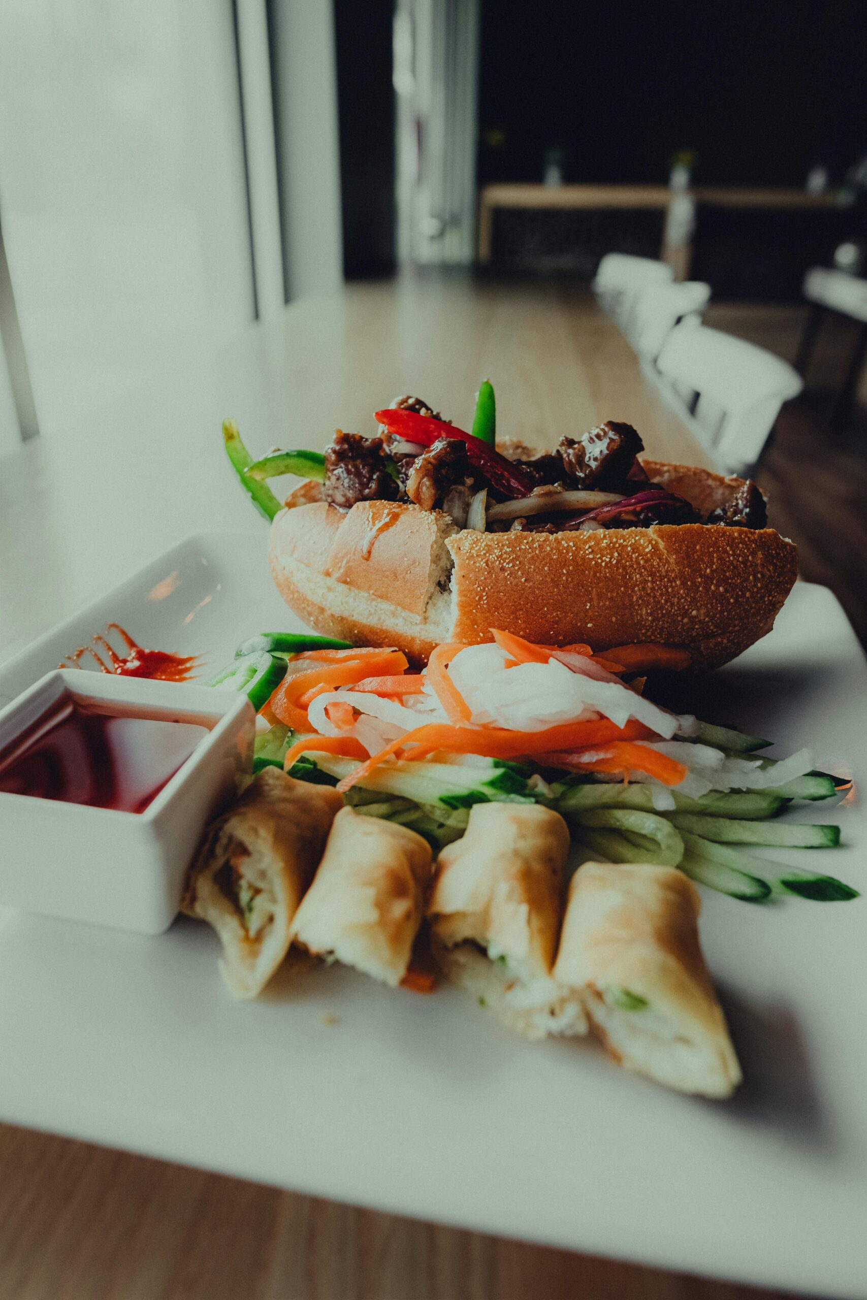 A mouth-watering Banh Mi sandwich with fresh spring rolls served on a white plate.